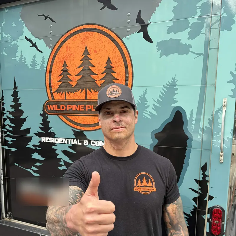 A Wild Pine technician giving a thumbs up beside the company van